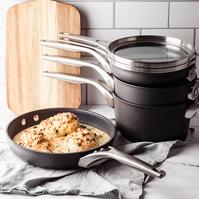 Skillet with chicken in it and stacked pots and pans behind it